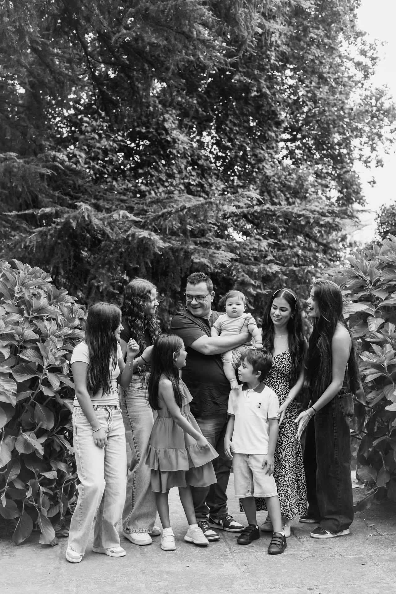 Família numerosa em jardim com hortênsias e árvores, todos em tons neutros, retrato em preto e branco ao ar livre, Susana Schmitz Fotografia, Porto