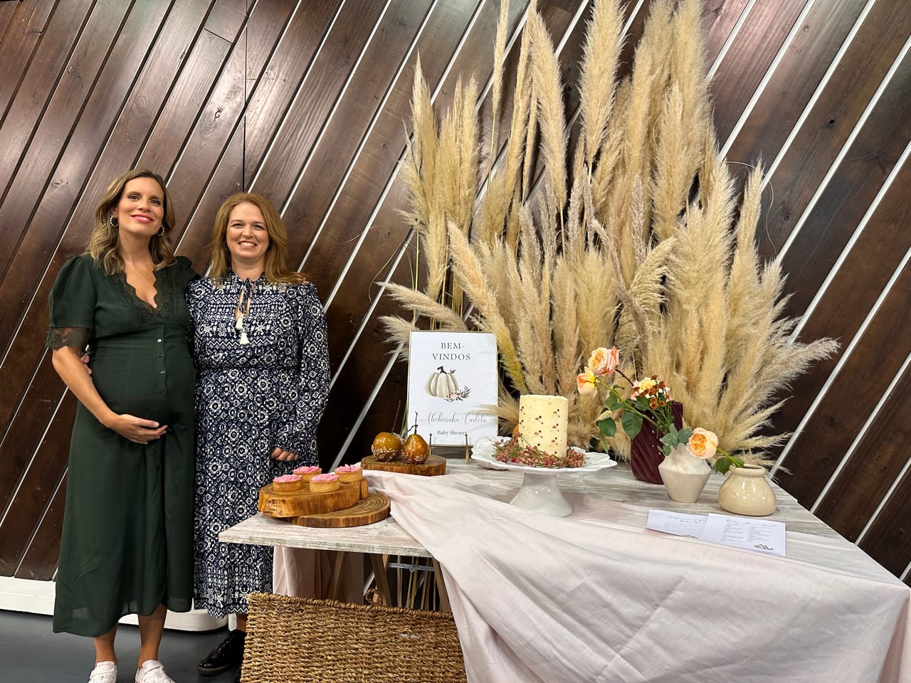 Susana Schmitz com a apresentadora do programa Filhos e Cadilhos junto ao cenário de Baby Shower decorado com pampas e bolo, Porto Canal, 2022