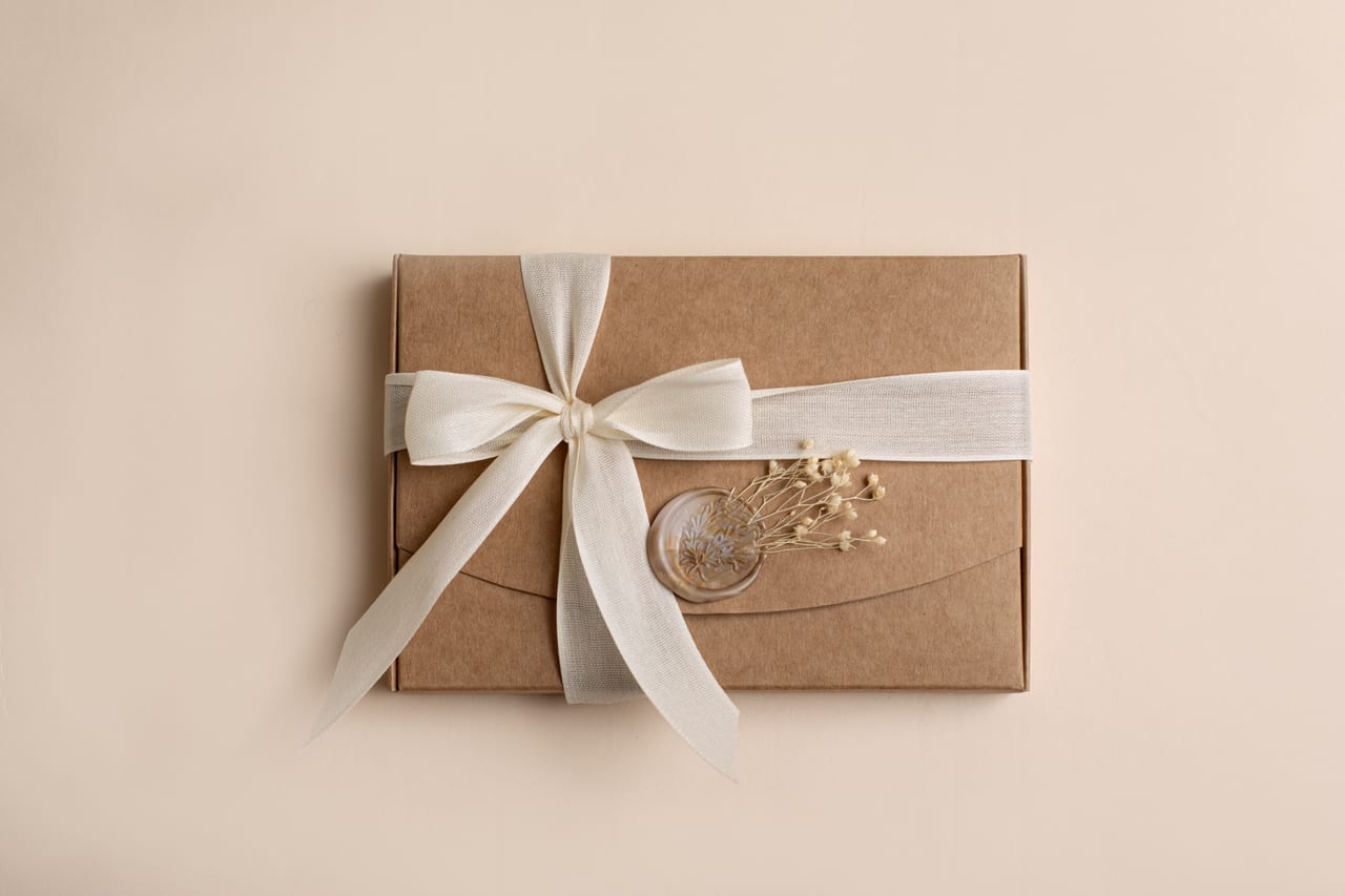 Caixa kraft de presente vista de cima com fita de cetim creme, selo de lacre e ramo de flor seca, packaging Susana Schmitz Fotografia, Porto