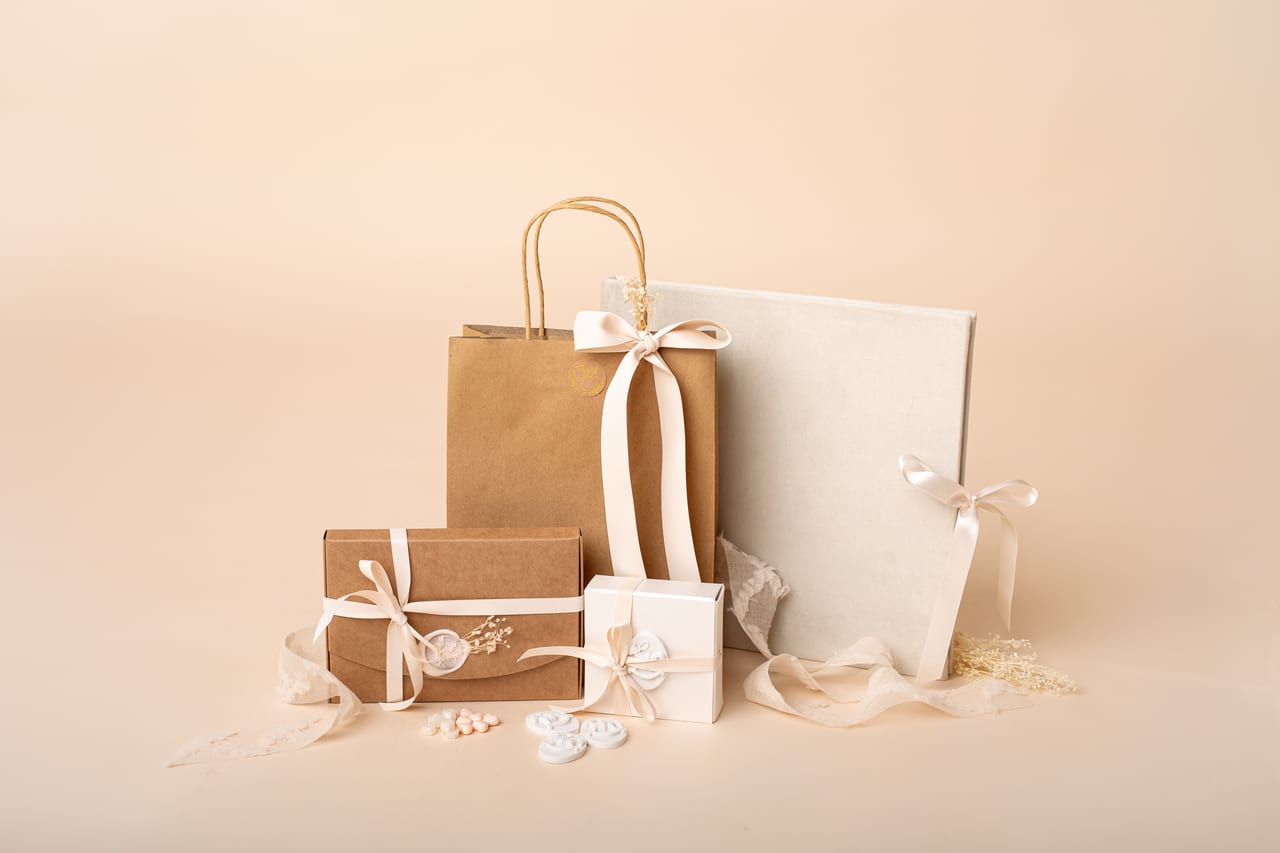 Apresentação do packaging Susana Schmitz Fotografia: saco kraft, caixas com fita de cetim, álbum em linho creme e flores secas sobre fundo pêssego, Porto