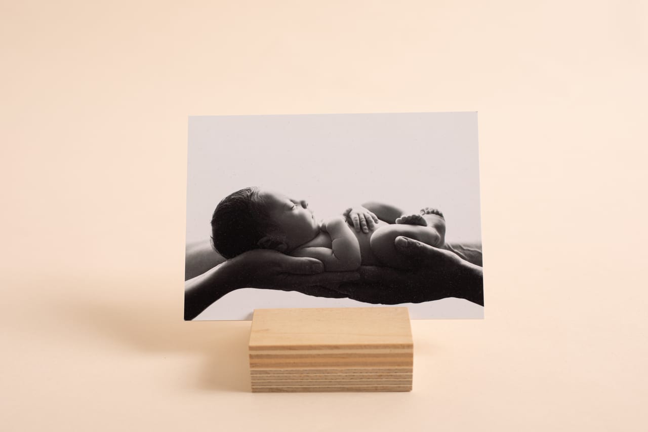 Boutique print a preto e branco com fotografia de recém-nascido nas mãos do pai, exposto sobre suporte em madeira, Susana Schmitz Fotografia, Porto