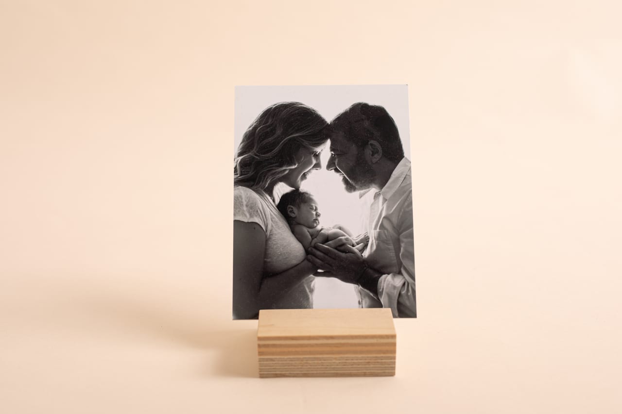 Boutique print a preto e branco com fotografia de pais a tocar testas com recém-nascido nas mãos, sobre base de madeira, Susana Schmitz Fotografia, Porto