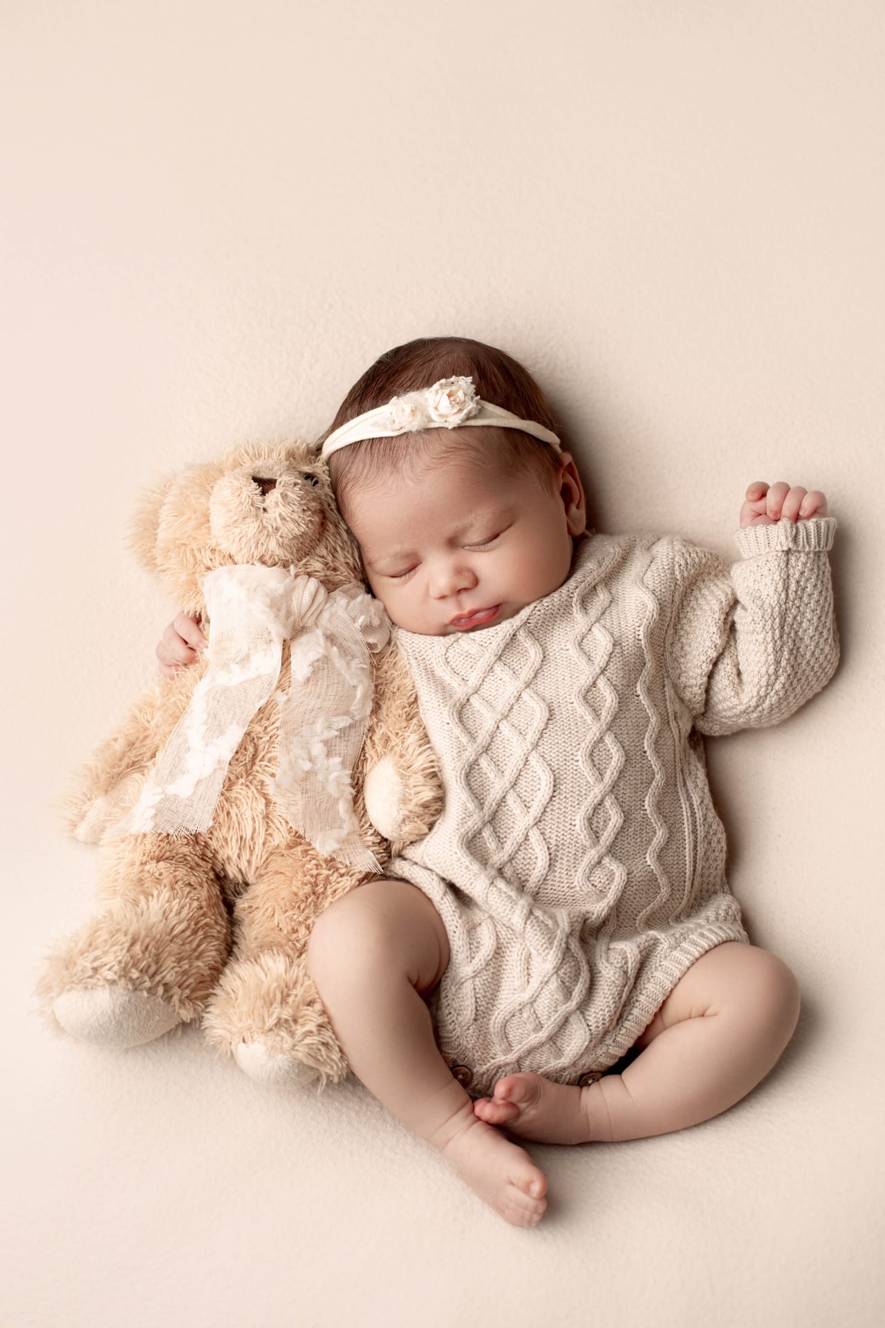 Bebé recém-nascido a dormir com fato de malha bege e bandolete, abraçada a urso de peluche, Susana Schmitz Fotografia, Porto