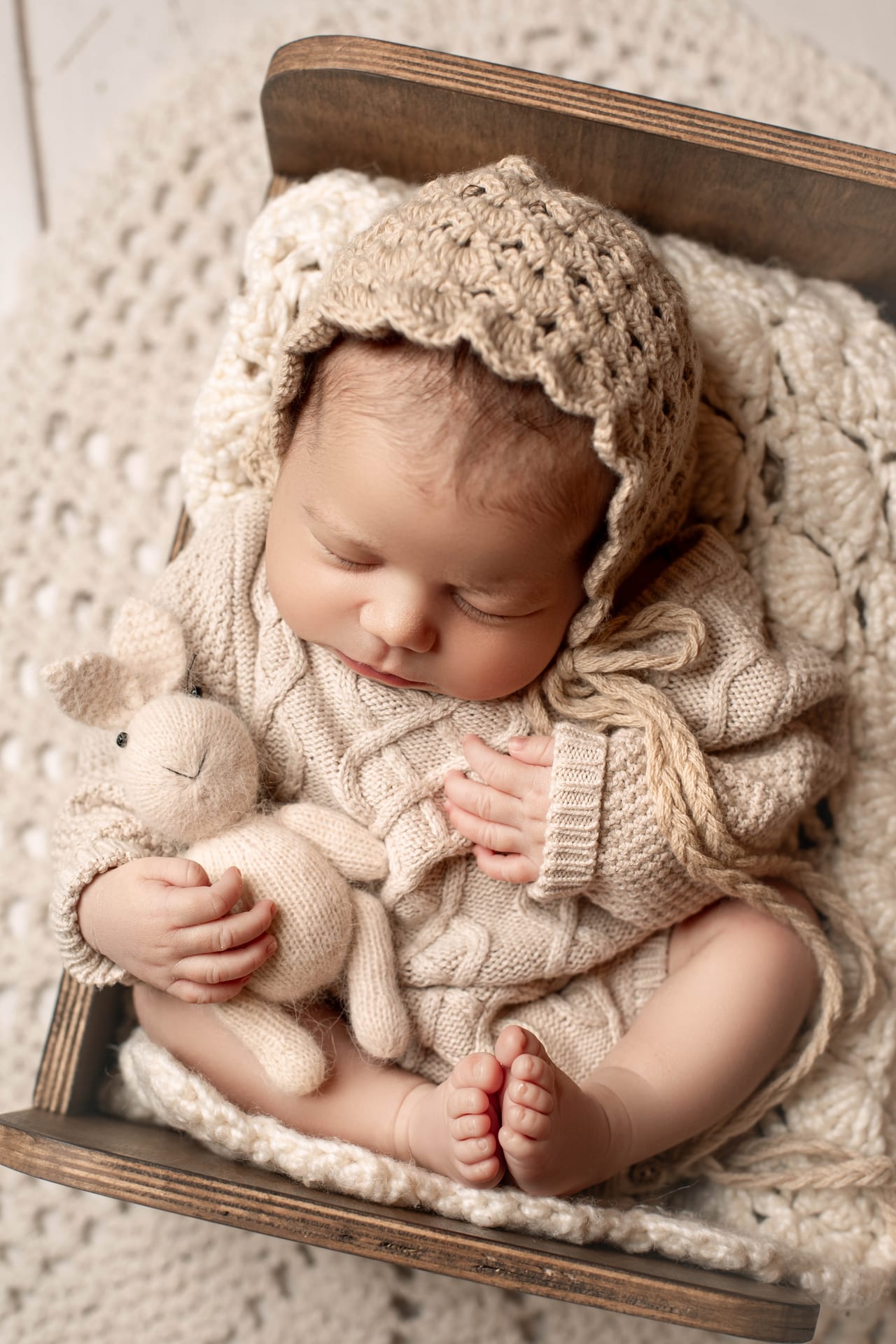 Bebé recém-nascido a dormir com touca de croché e coelho de peluche em cama de madeira, Susana Schmitz Fotografia, Porto