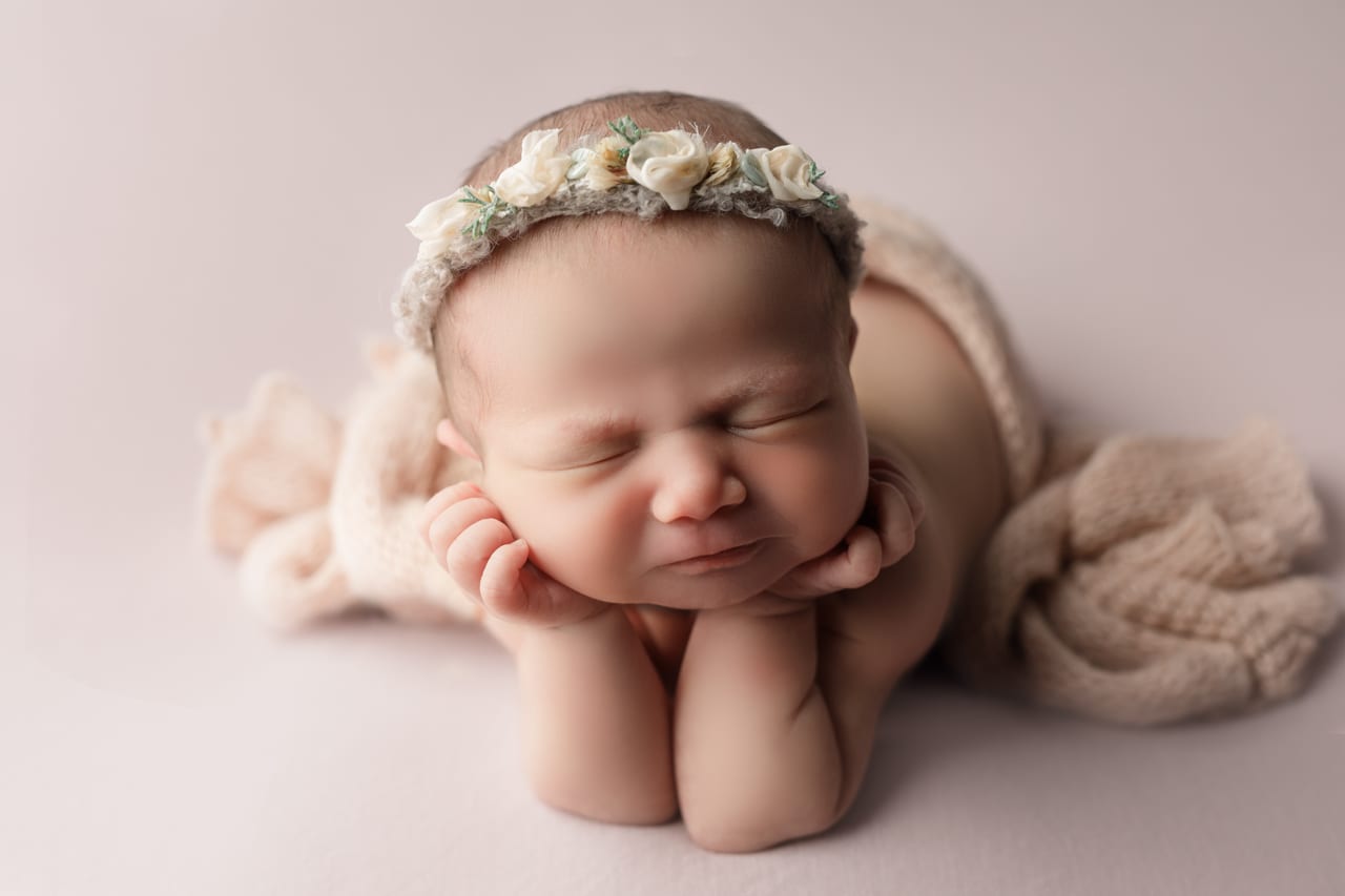 Recém-nascida a dormir em pose froggie sobre as mãos, com bandolete de flores brancas, manta de malha bege, sessão em estúdio, Susana Schmitz Fotografia, Porto